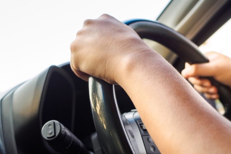 closeup of two hands on a car steering wheel